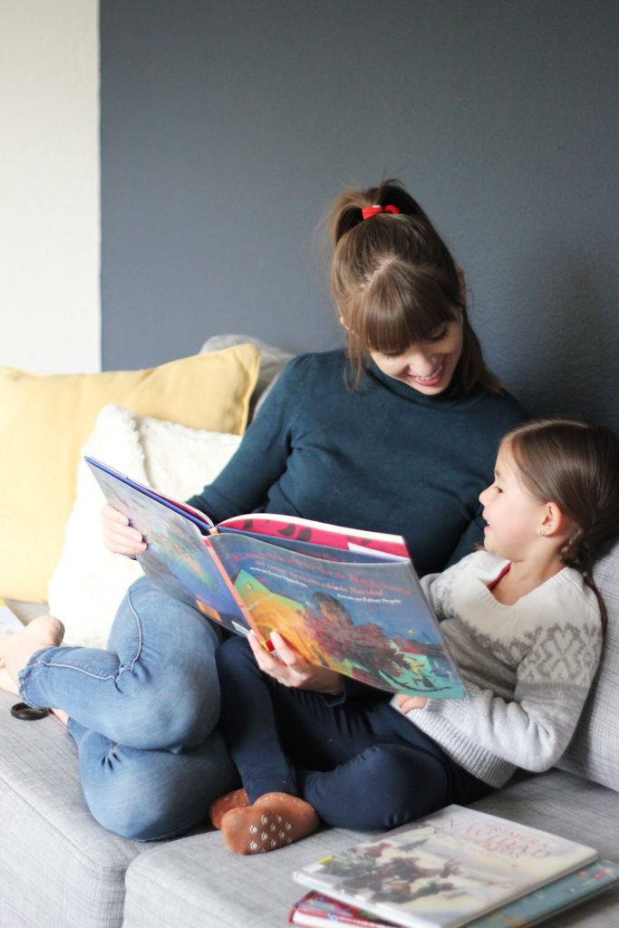 mom and toddler laughing with Spanish Christmas books in front