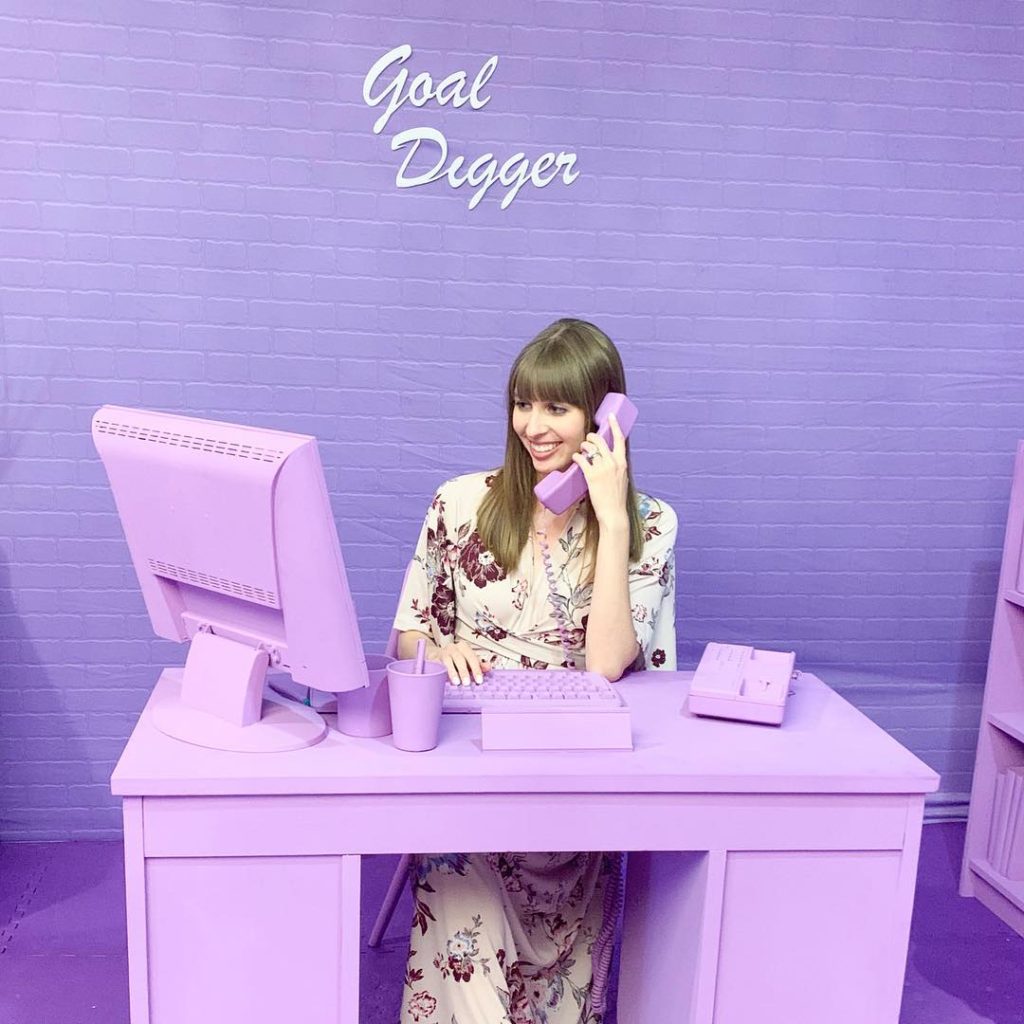 Woman sitting at purple desk on purple phone
