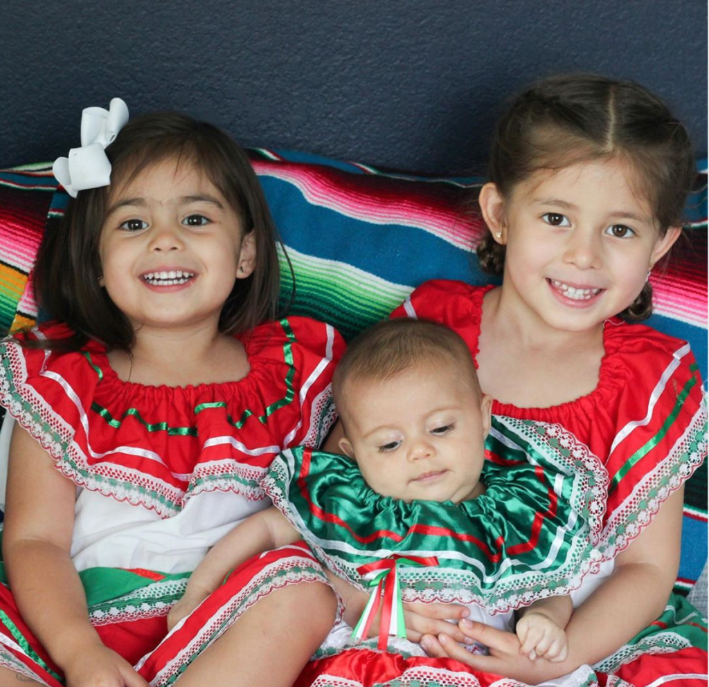 Three little girls dressed in typical Mexican dresses for Hispanic Heritage Month. 