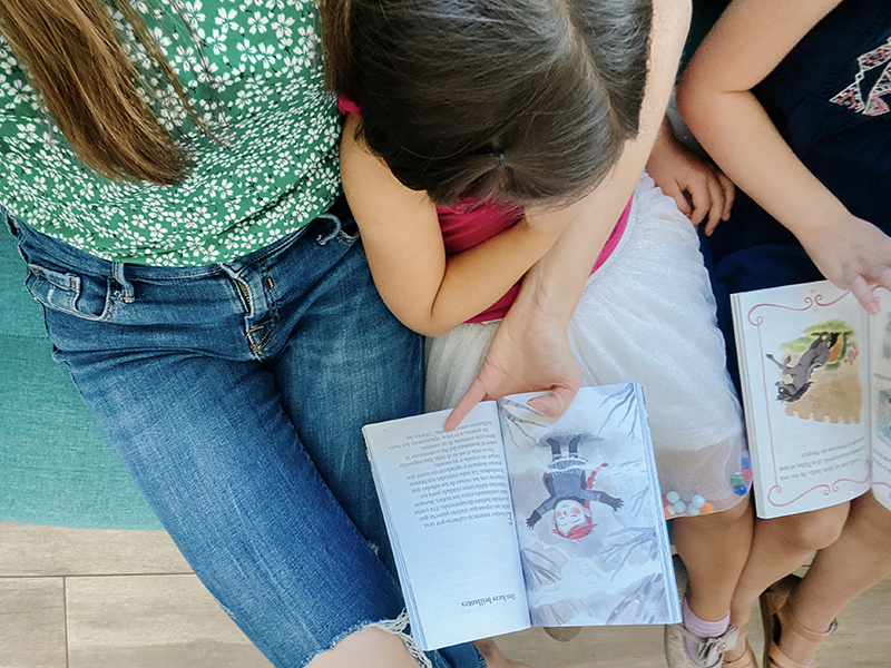 Overhead shot of a mom reading with her two daughters. 