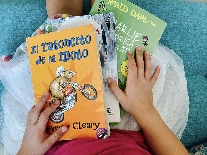 Three Spanish chapter books for preschoolers in a little girl's lap. 