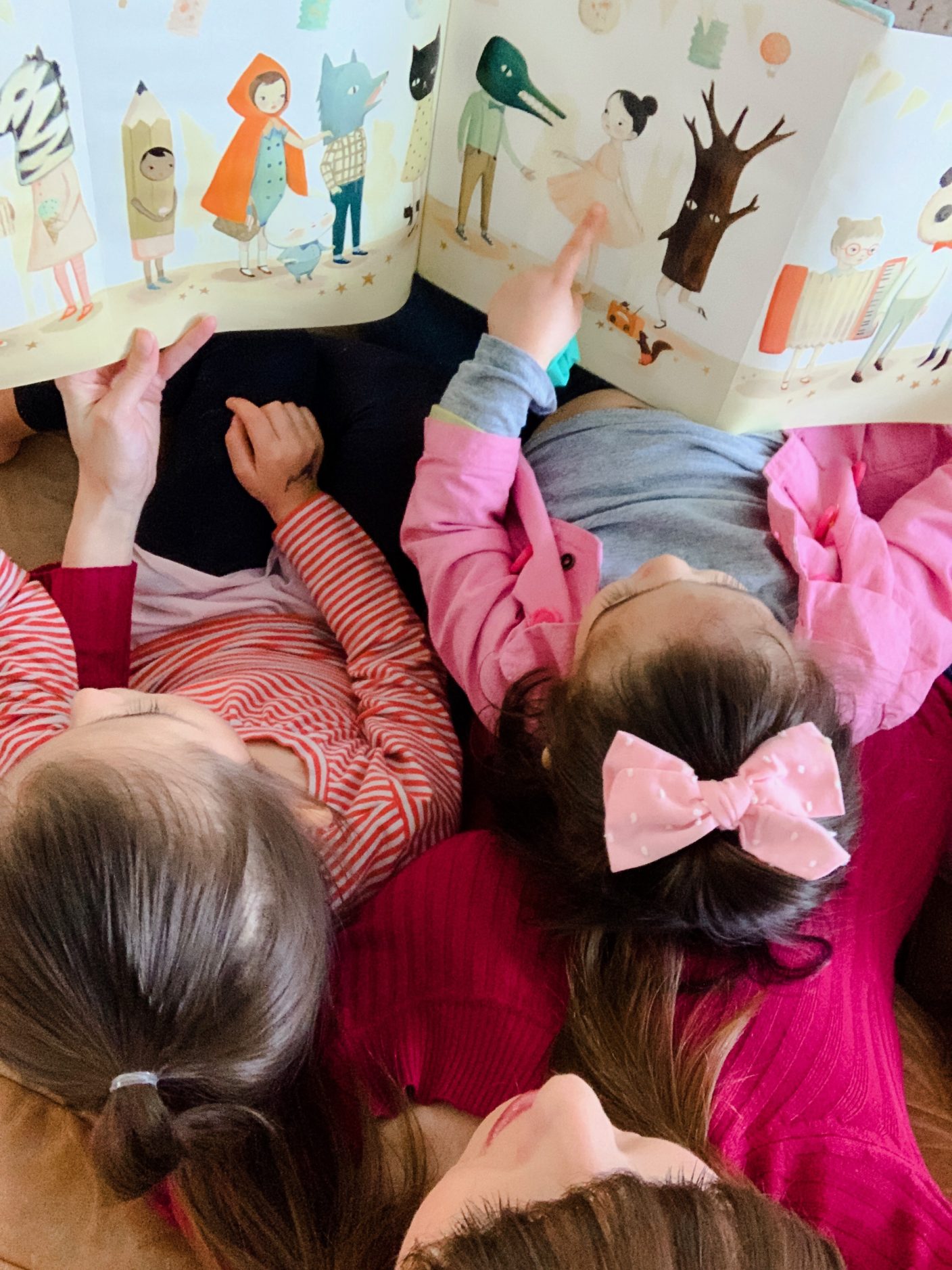 Mom and two daughters reading on couch.